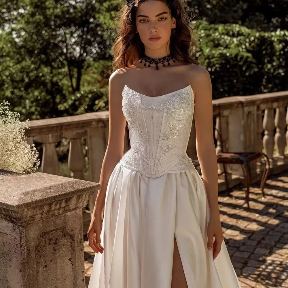 Appliquéd embellished bodice strapless wedding gown. A-line silhouette with dropped waistline available in white or ivory satin