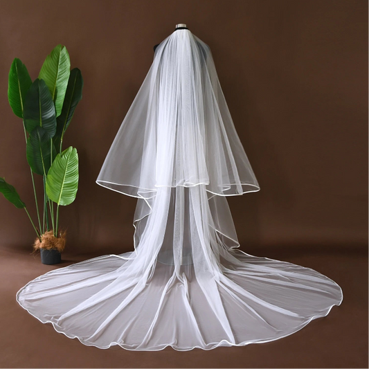 White cathedral-length bridal veil with layered tulle and satin-trim finish on model