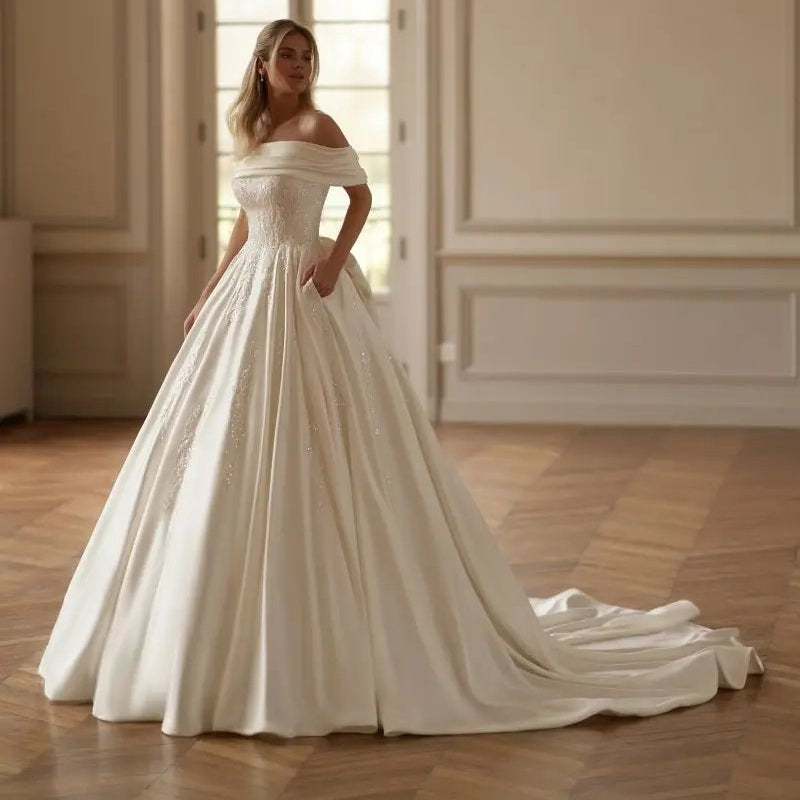 Off-shoulder beaded satin bridal gown with voluminous pleated off-white skirt
