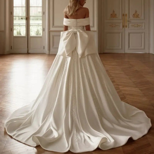 Satin wedding dress has an off the shoulder design with a large back bow and court train sizes 2-26w