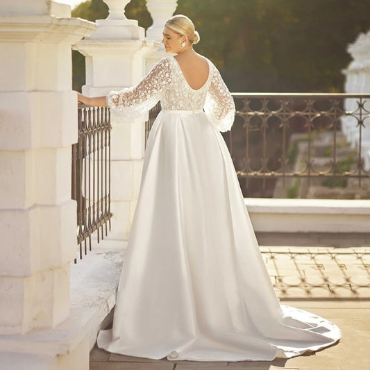 White satin A-line wedding dress with lace sleeves and flowing skirt, belted waist