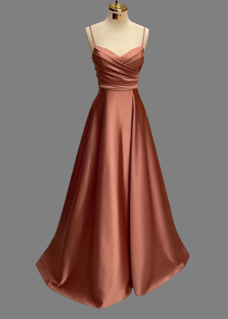 A floor-length satin A-line dress with spaghetti straps and a pleated bodice, displayed in a salmon pink color.