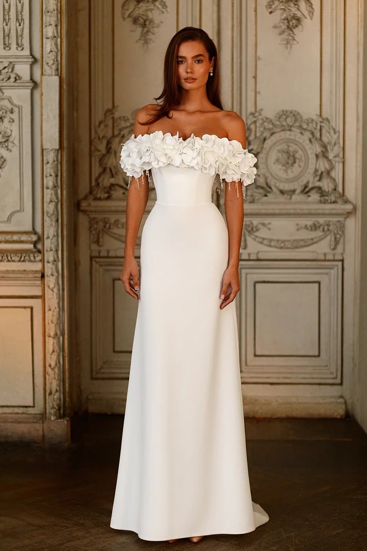 3D flower band on an off the shoulder bodice made in stretch jersey crepe fabric. Floor length with a small sweep train in white or ivory colour sizes 2-26w