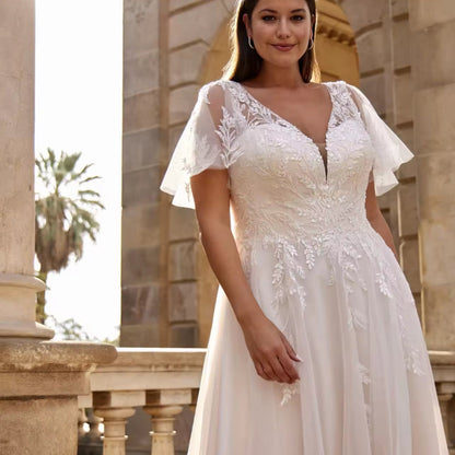 Ivory lace wedding dress with V-neckline, detailed appliqué bodice, and flutter sleeves