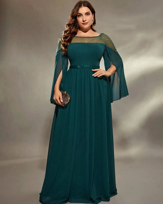 Woman wearing a teal evening gown with sheer sleeves against a gray background