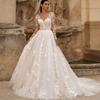 White illusion lace wedding dress with long sleeves, floral appliqué bodice, full skirt