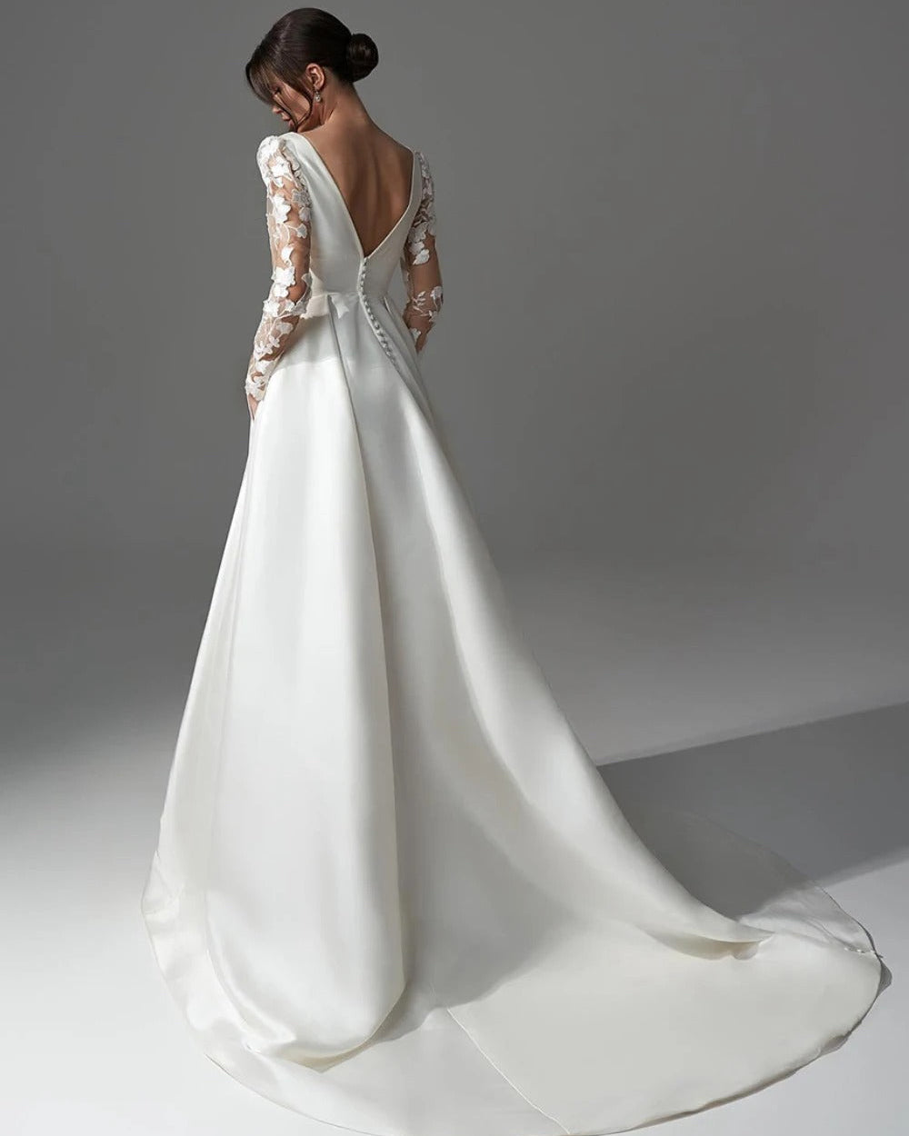 Ivory satin wedding dress with lace long sleeves, open back, and flowing full skirt