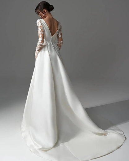 Ivory satin wedding dress with lace long sleeves, open back, and flowing full skirt