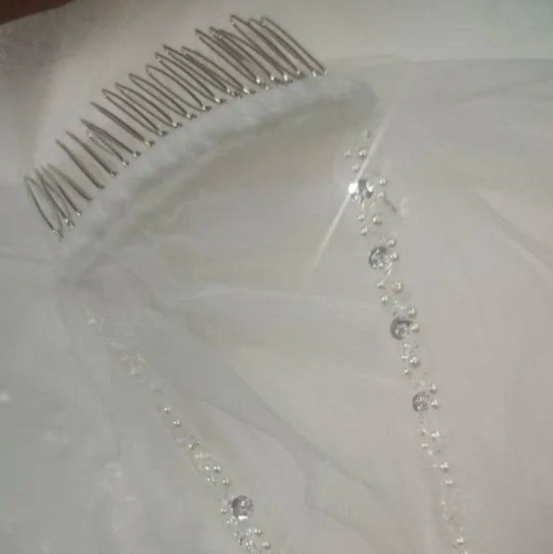 Ivory wedding veil closeup: beaded border and comb with pearl details