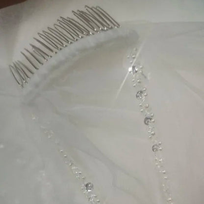 Ivory wedding veil closeup: beaded border and comb with pearl details
