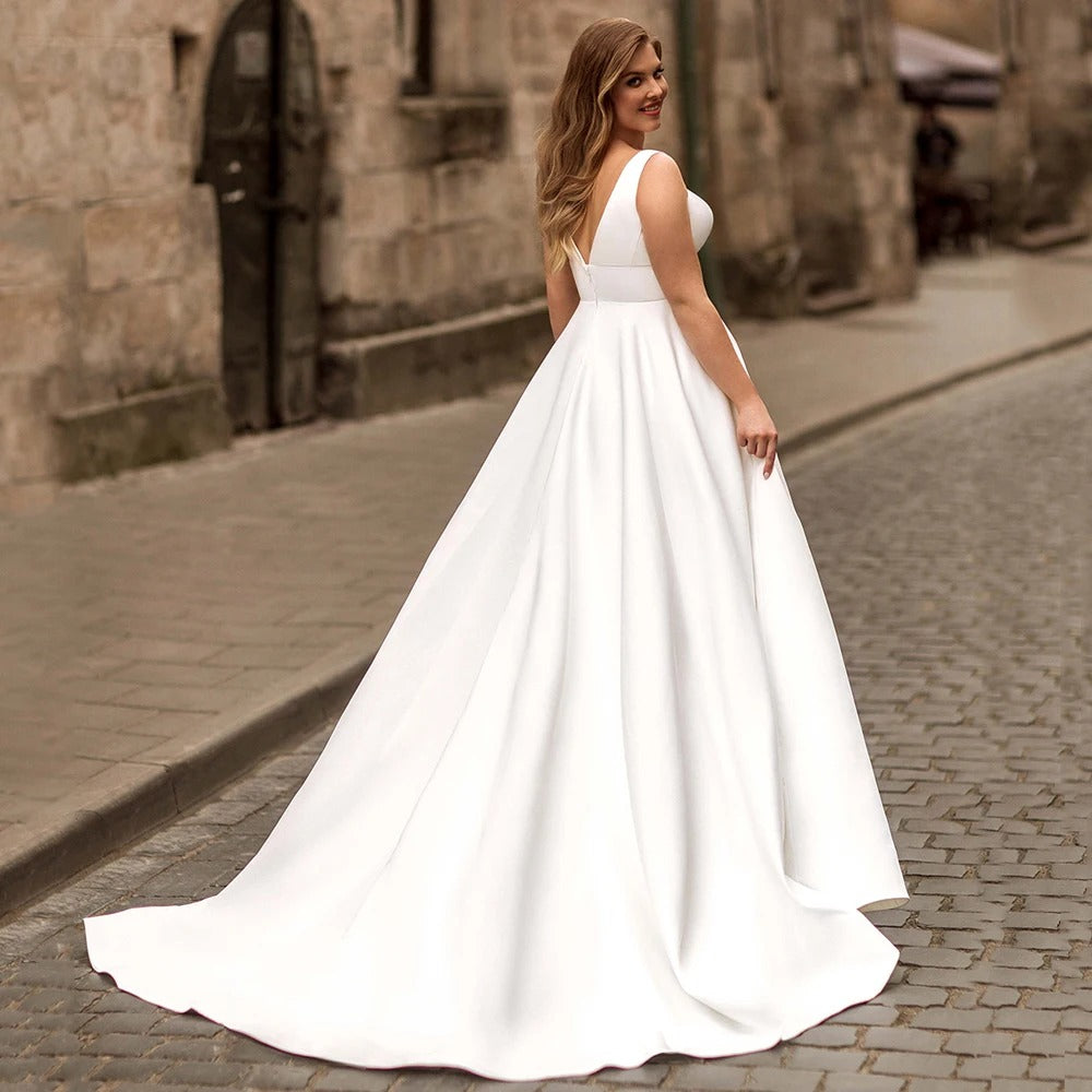 White satin sleeveless wedding dress with V-neck, fitted waist, flowing A-line skirt.