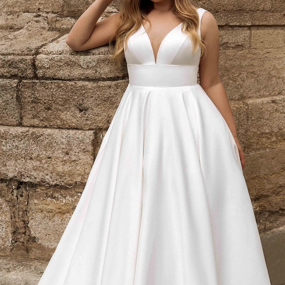 White satin sleeveless wedding dress, deep V-neck bodice, gathered waist, full skirt.