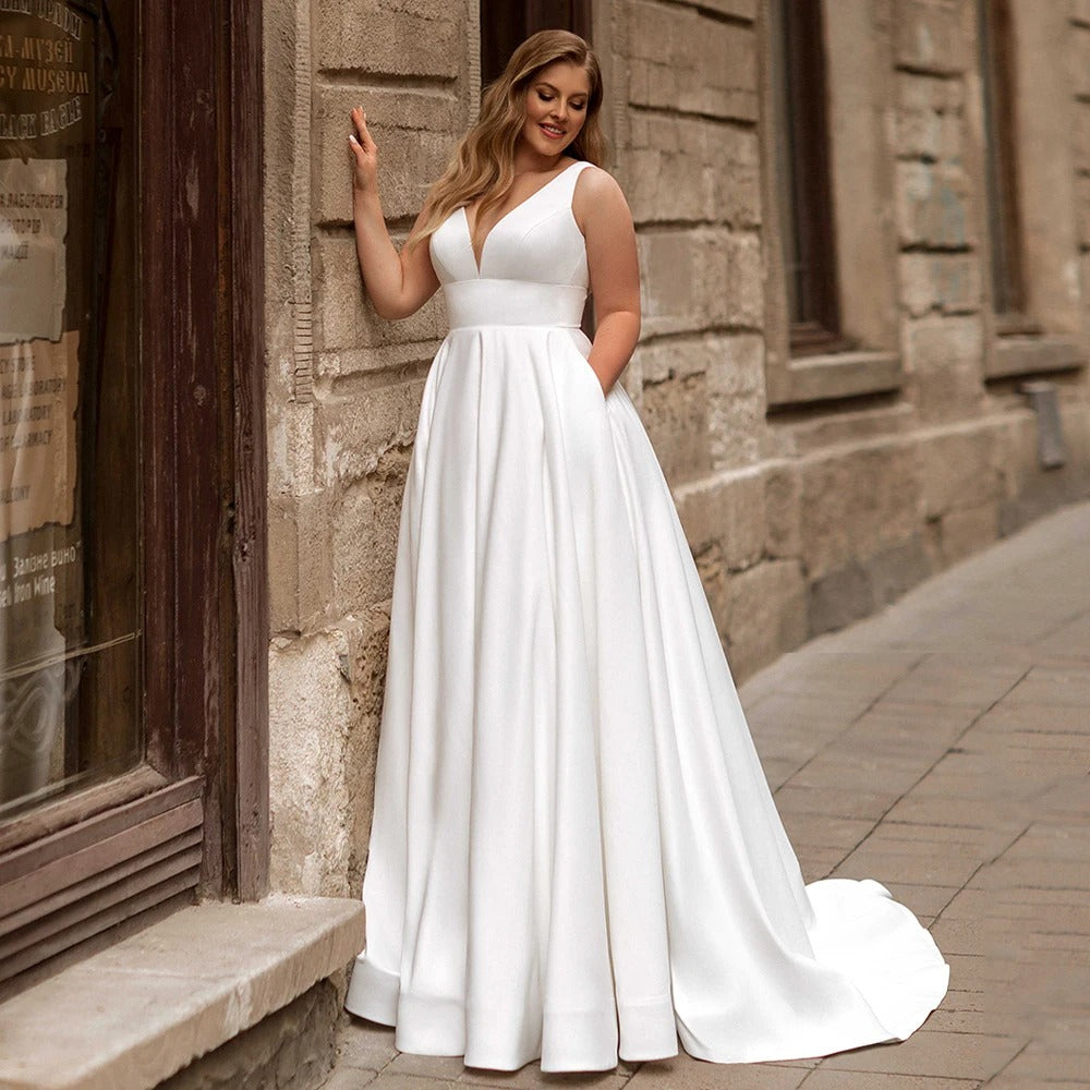 White satin sleeveless wedding dress, V-neck bodice, fitted waist, full A-line skirt.