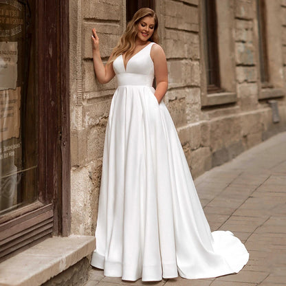 White satin sleeveless wedding dress, V-neck bodice, fitted waist, full A-line skirt.