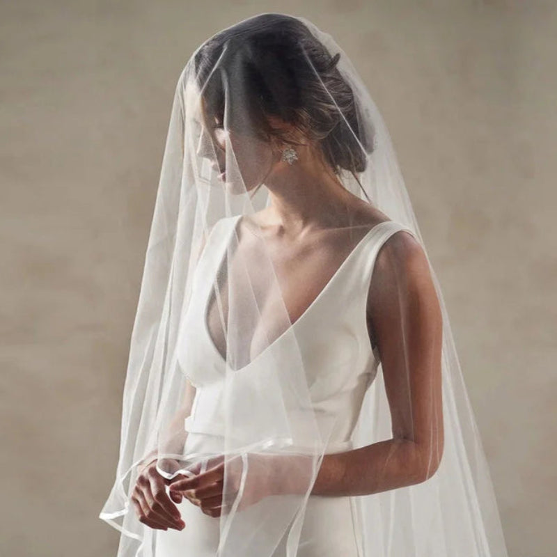 White two-tier wedding veil with sheer face-covering and layered cathedral drape