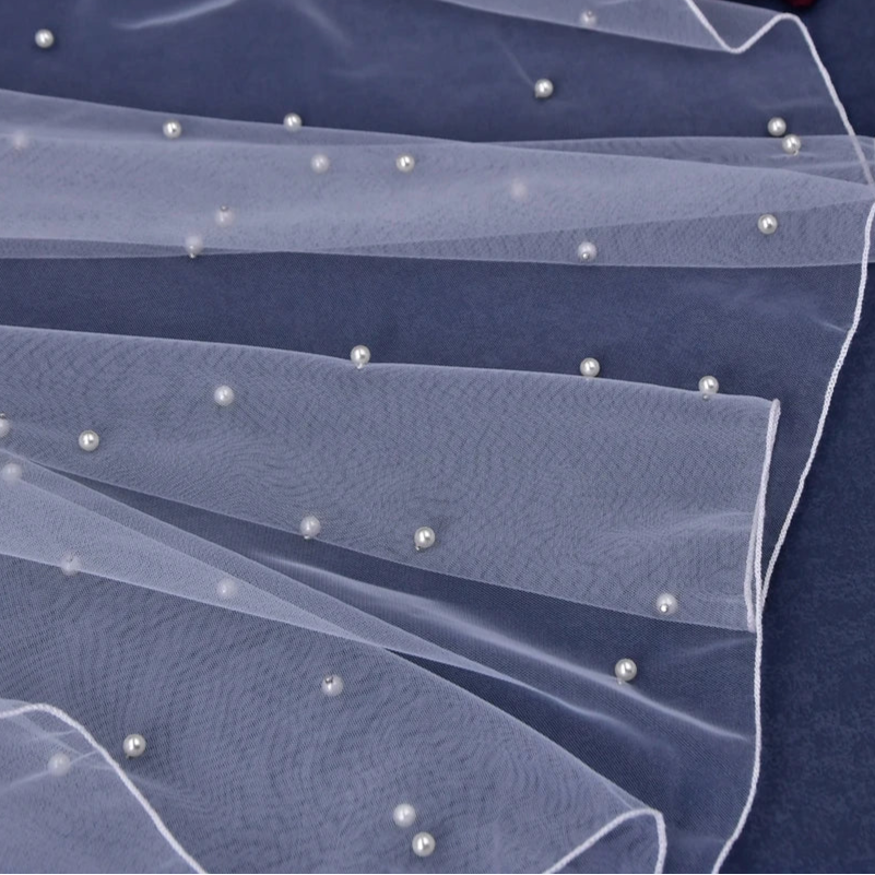 Elbow-length veil with dark tulle layers and small pearl-like bead details along edge