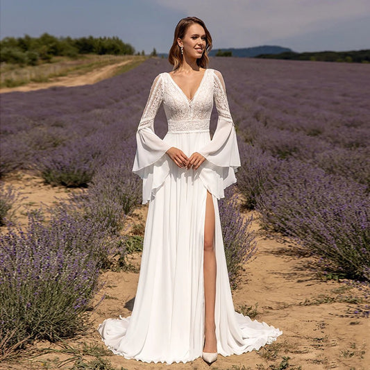 Bride in a lavender field in a boho inspired chiffon and lace wedding dress. V-neck with bell sleeves leg split and a sweep train available sizes 2-26 